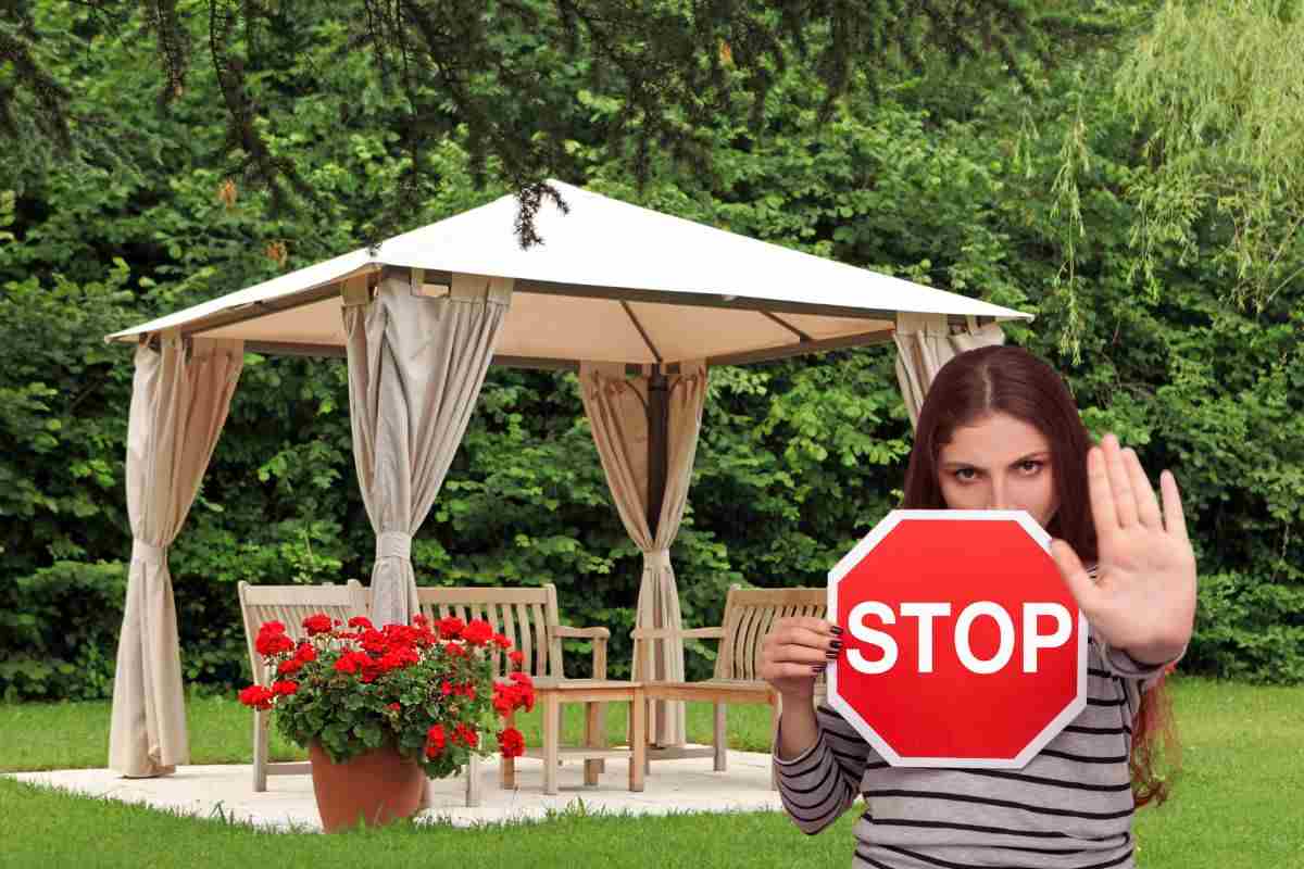 un gazebo in giardino ed una ragazza che tiene il cartello dello stop