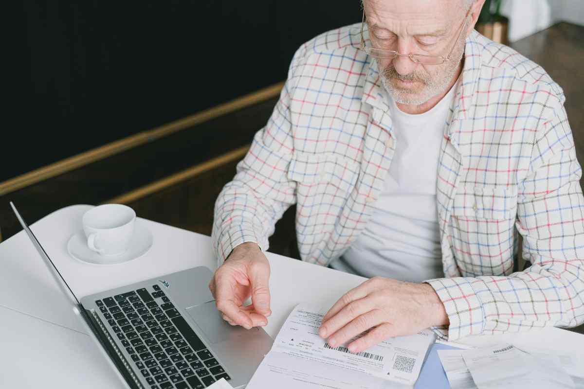Uomo che legge un documento con davanti il computer