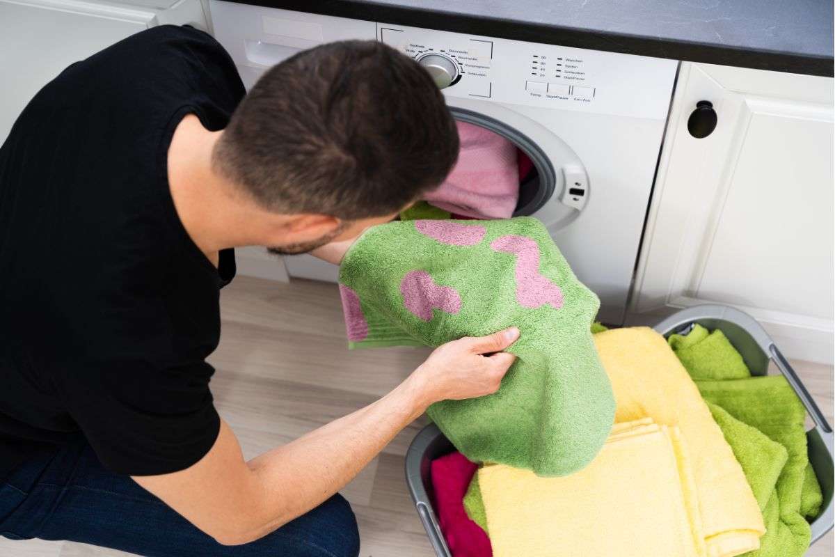 un ragazzo guarda le macchie di candeggina sui vestiti