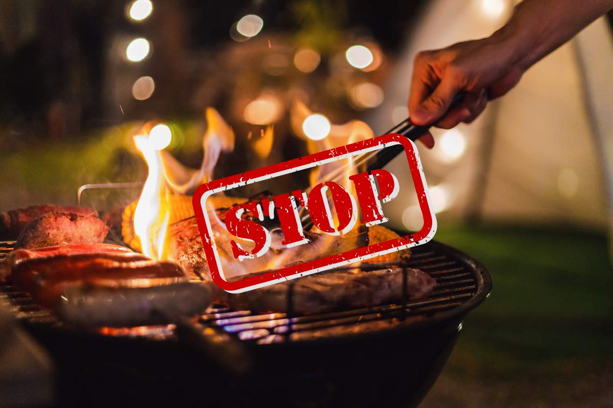 Persona che fa il barbecue con una scritta di Stop in primo piano