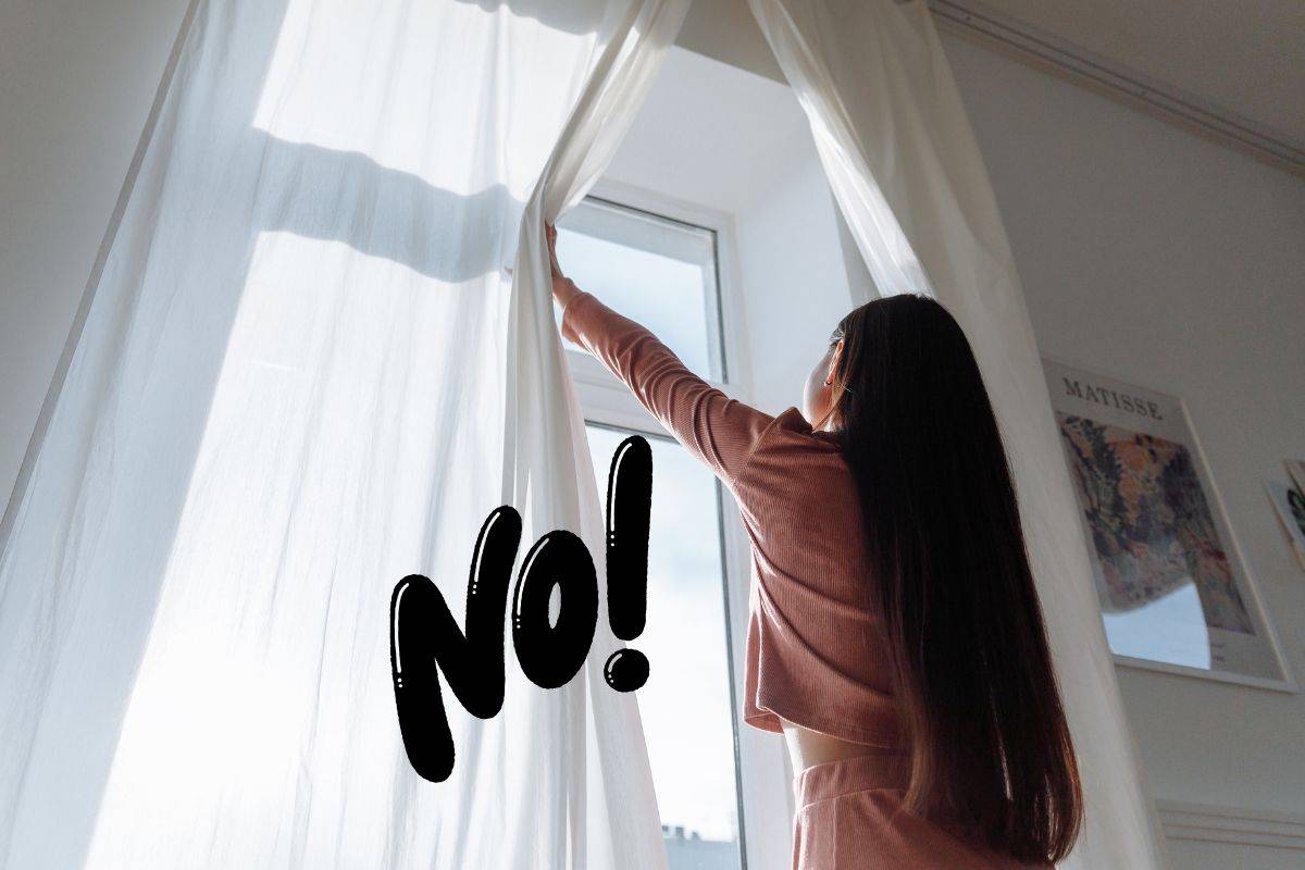 una ragazza che chiude le tende di casa e la scritta no